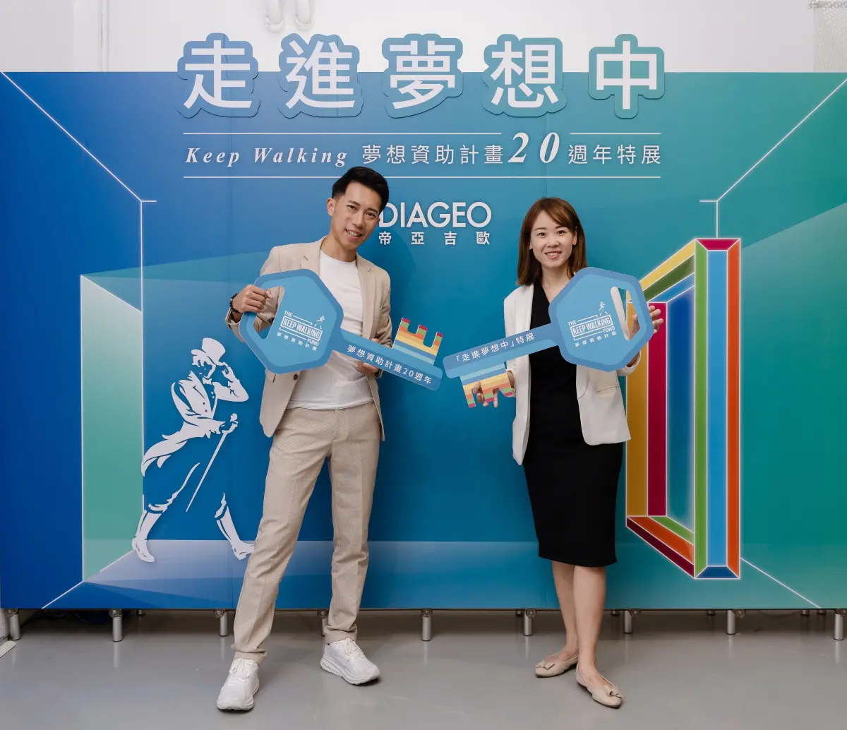 ▲年度大使 陳彥博（左）、帝亞吉歐台灣公共事務部總監 謝翠娟 手拿夢想鑰匙於 KEEP WALKING 夢想資助計畫 20 週年特展「走進夢想中」主視覺前合影。（圖／廠商提供）