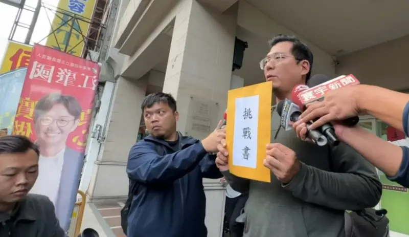 ▲羅廷瑋服務處主任石國勳拿著挑戰書,跑到江肇國服務處前開記者會。(圖/羅廷瑋競總提供,2023.12.18)