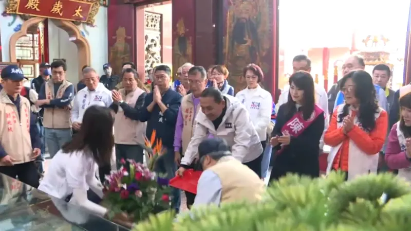 ▲國民黨總統候選人侯友宜在前金萬興宮參拜，獻花時放在盤上的花卻在鞠躬的時候不慎滑掉在地上，侯友宜也嚇到。（圖／民眾提供）