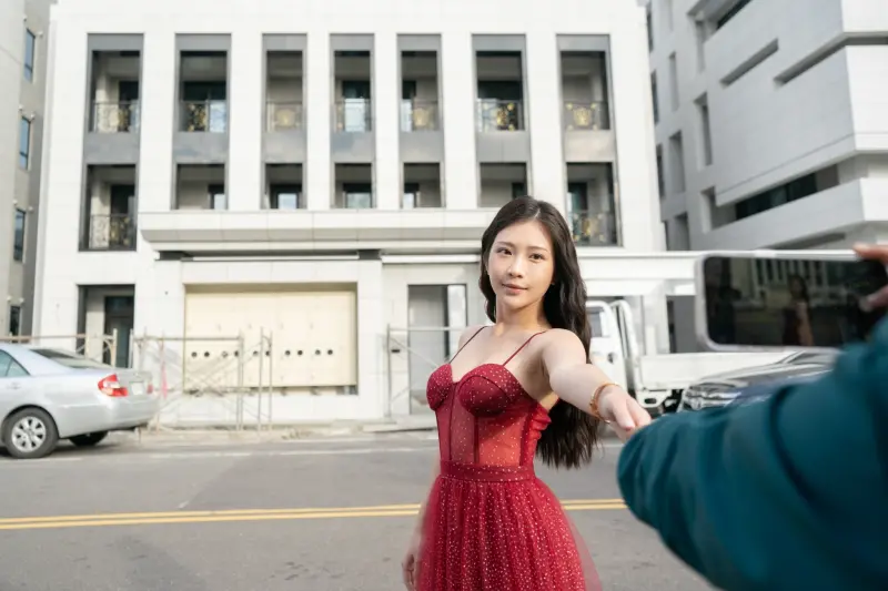 ▲鄭家純寒風中穿著紅色禮服,在謝衣鳳家門口拍網美照。(圖/吳音寧競總提供,2023.12.24)