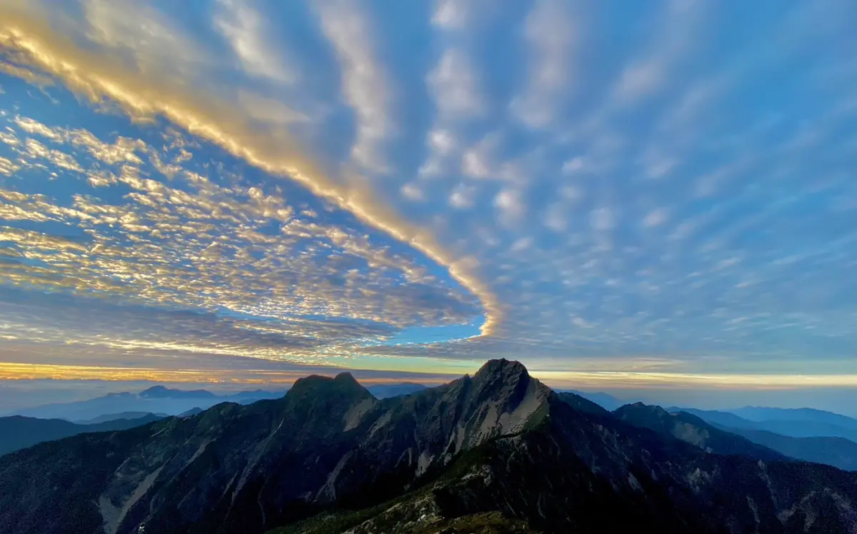 ▲玉山出現高積雲、氣流配合的絕美場景，天空彷彿被弧線隔成兩個世界。（圖／玉山氣象站提供）