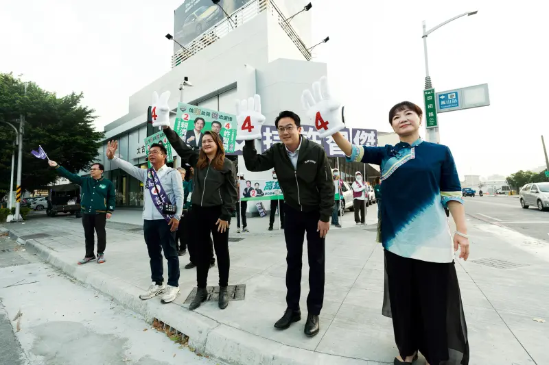 ▲立委許智傑與局處首長不斷向路過通勤族揮手、鞠躬致意，也戴著大型的四號手套，呼籲民眾禮拜六記得要出門投票。（圖／賴蕭配競辦提供）