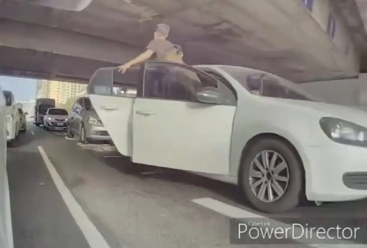 ▲2名男子行經中正路交流道路口疑似突然變換車道不板被按喇叭，站立在車門處對後方車輛叫囂。（圖／截自「翻轉台灣交通違規交流平台」）