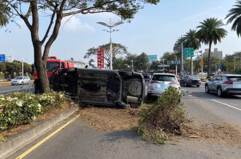 ▲大年初二、11日下午，高雄市19歲杜姓男子，駕駛汽車行經小港區平和東路口時，不慎擦撞中央分隔島及路樹，整台車翻覆、波及對向來車，釀2車碰撞4處擦挫傷送醫。（圖／翻攝畫面）