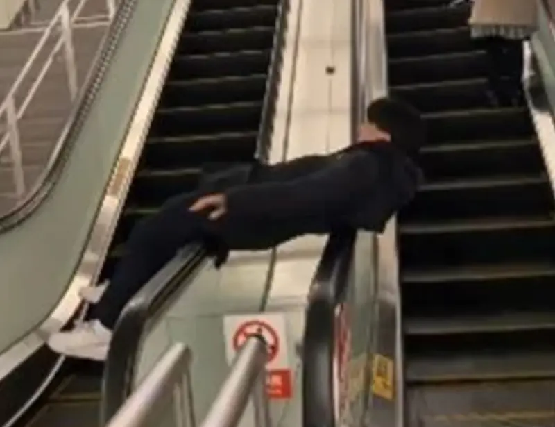 ▲夢想當迴轉壽司？身穿帽T的男子躺在捷運電扶梯上嬉鬧，而拍攝者也邊看邊笑，影片引發網路熱議。（圖／翻攝畫面）