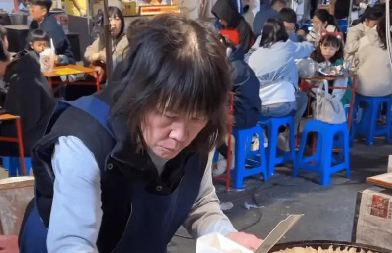 ▲在台南夜市擺攤賣煎餃的阿姨造型、臉型撞臉「伍佰老師」爆紅，最近在社群引起討論。（圖/Tik Tok）