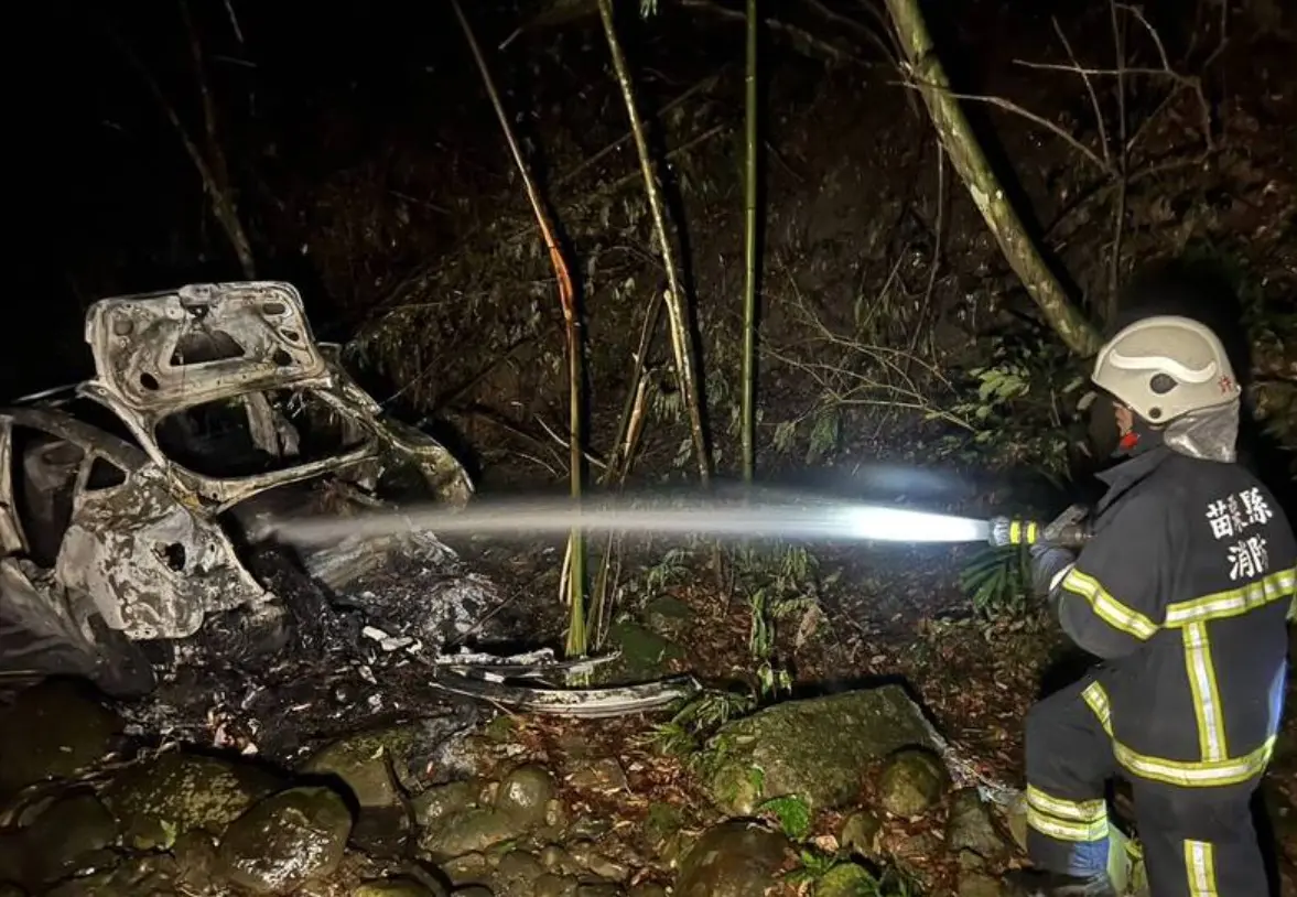 ▲16日晚間，苗栗縣獅潭鄉百壽村一處農路旁，一台特斯拉轎車翻落溪谷、起火燃燒，所幸38歲賴姓駕駛緊急逃生、僅受輕傷。（圖／翻攝畫面）