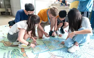 ▲葳格小學師生在文化週裡，藉由希臘巨型地圖，認識並討論地圖上的希臘著名景點與文化。(圖／葳格小學提供）