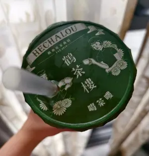 ▲網友到鶴茶樓買飲料後，發現封膜上的細節，原來鶴茶樓是「喝茶嘍」的諧音。（圖/絨茸容臉書）