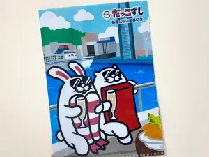 ▲壽司郎為去年開幕的基隆站前店紀念限定款資料夾，畫出鮮蝦兔和鮪魚小萌獺在港邊喝香檳的模樣。（圖／記者蕭涵云攝）