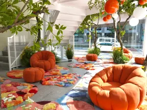 ▲大量橘子擺設匯聚成橘子林，象徵著「聚吉」好運。在入口處的設計色彩繽紛的地毯和橘子小沙發，供民眾放鬆交流。（圖／業者提供）