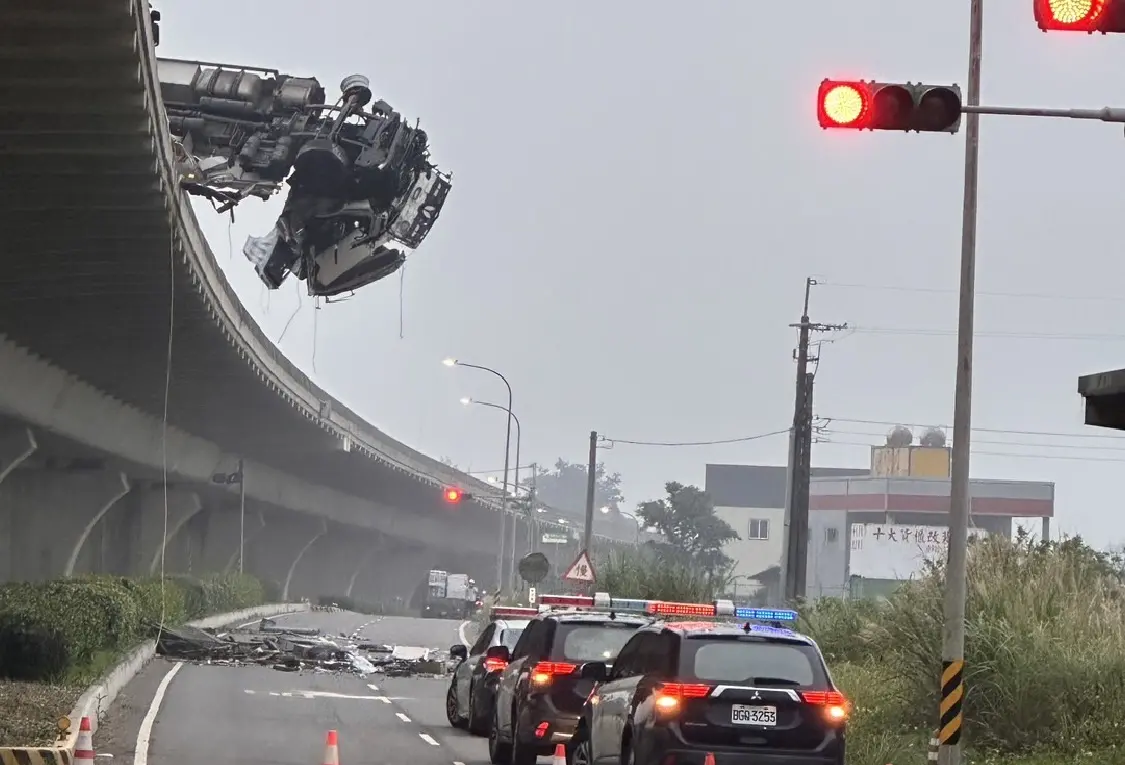 ▲13日凌晨，台61線南向52公里處，發生重大車禍事故，一台聯結車衝出護欄懸掛在橋外，駕駛從橋上墜落送醫不治，車體零件及護欄碎石落下，也波及橋下路過的2名機車騎士。（圖／翻攝畫面）