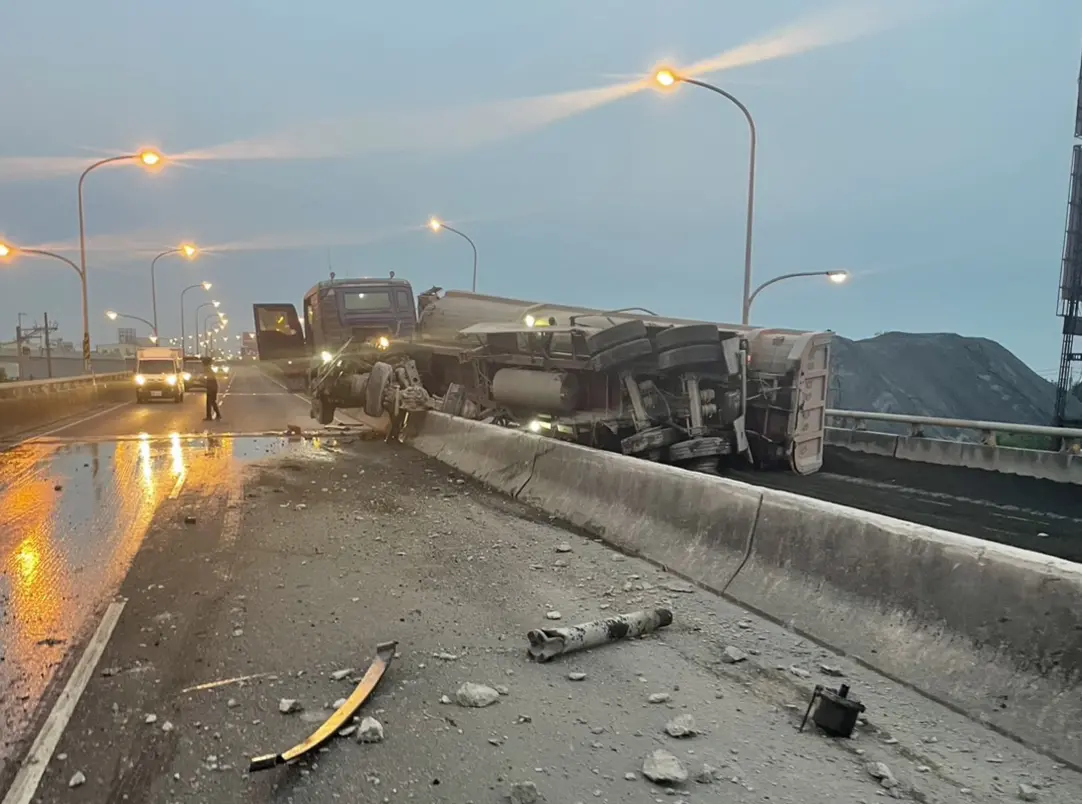 ▲一輛砂石車從屏東方向往高雄行駛，不明原因自撞護欄後，翻覆橫躺在車道，車頭更「掛」在護欄上，現場一片狼籍。（圖／翻攝畫面）