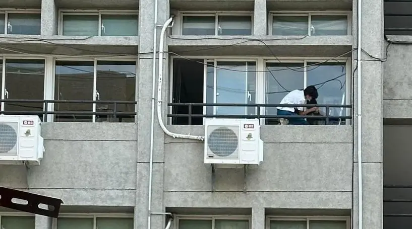 ▲民眾拍到女學生蹲在窄小的窗台，拿著抹布擦玻璃。（圖／江和樹提供，2024.05.02）