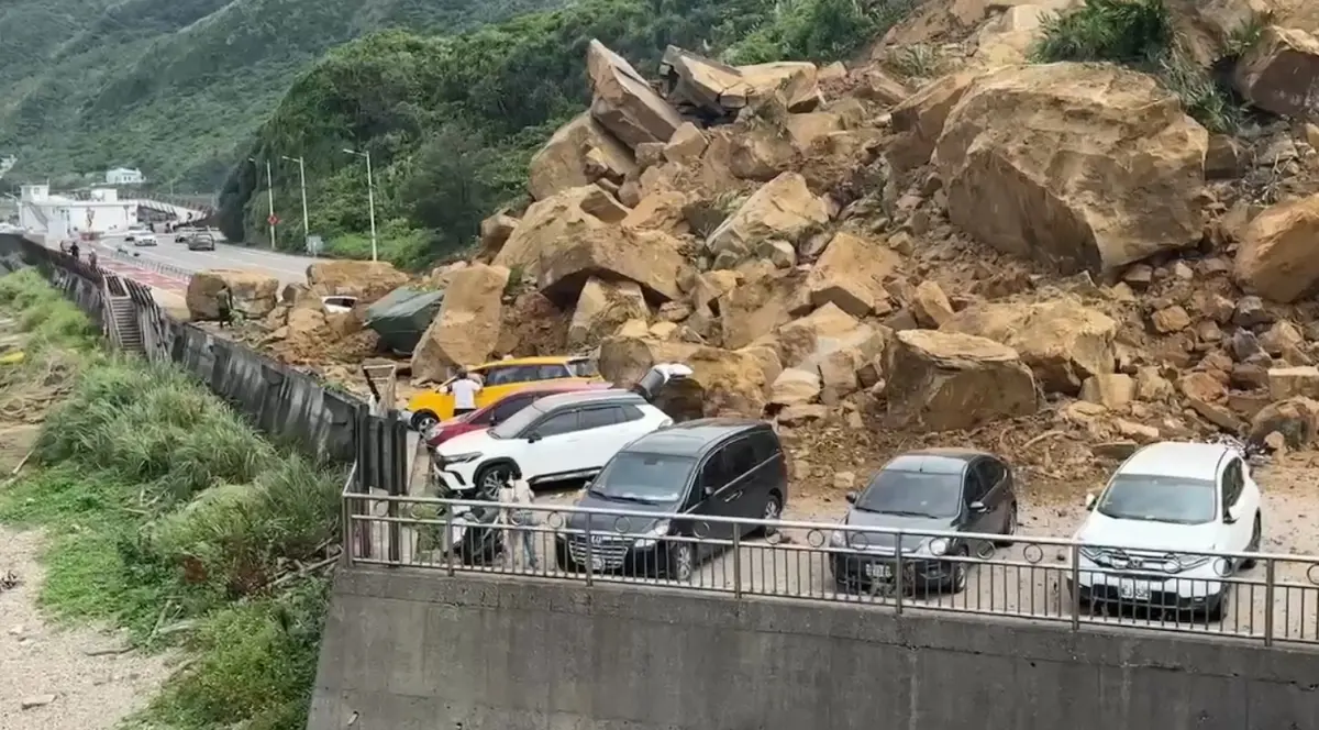 ▲3日下午，基隆潮境公園大橋入口處，發生大片土石崩落，整片山壁、巨石不斷落下，壓毀下方多輛汽車。（圖／翻攝畫面）