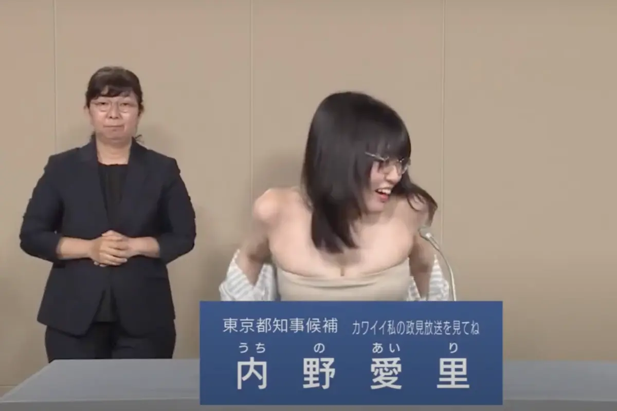 ▲日本東京都知事選舉即將在7月7日舉行，一位31歲女參選人內野愛理，昨（27）日在政見發表會上，脫掉上衣只穿平口小可愛，在桌前名牌遮掩下，視覺效果宛如全裸，讓一旁手語老師傻眼。（圖／翻攝自內野愛理的YouTube）