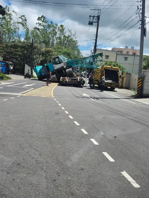 ▲吊車在彎道處突然向左傾斜掉下拖板車，意外砸中路邊垃圾車。（圖／翻攝畫面）