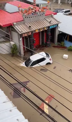 ▲高雄大社區鹽埕巷因大雨成為一片汪洋，導致一部白色車輛遭水流沖走。（圖／翻攝畫面）