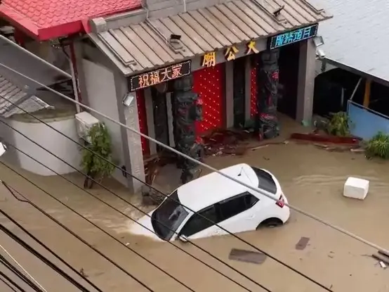 ▲高雄大社區鹽埕巷因大雨成為一片汪洋，導致一部白色車輛遭水流沖走。（圖／翻攝畫面）