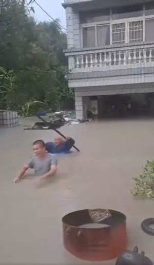 ▲台南關廟龜洞的透天厝，1樓全部泡水，住戶拿著長竿冒險涉水外出。（圖／王定宇臉書）