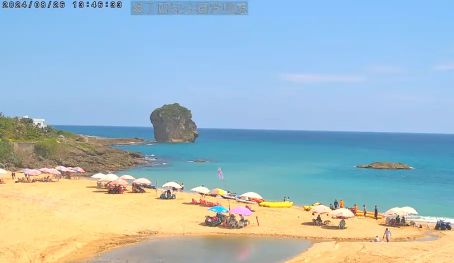 ▲今（26）日墾丁船帆石沙灘即時影像，可見仍有許多陽傘插在沙灘上，與昨天幾乎沒有差異，陽傘數量、位置也幾乎相同。（圖／翻攝自YouTube「ktnpworld」）