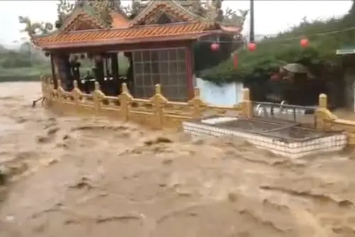 ▲新北市金山區今（4）日中午開始下起暴雨，雨水夾雜泥土成為滾滾黃流，幾乎將路旁的民宅寺廟全部淹沒，景象十分驚人。（圖／翻攝畫面）