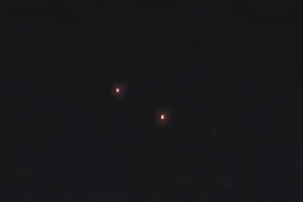 ▲這些神秘飛行物體發出鮮豔的粉色、橘色、黃色及紫色的光芒，且彼此之間維持固定距離緩慢而一致的移動。（圖／翻攝自影片截圖）
