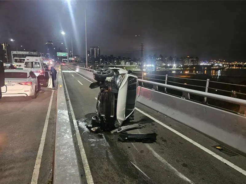 ▲白色自小客車疑因競速失控翻覆在機車道上。（圖／翻攝畫面）