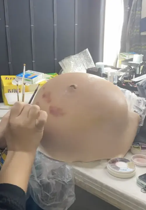 ▲化妝師細心為橡膠孕肚上色。（）