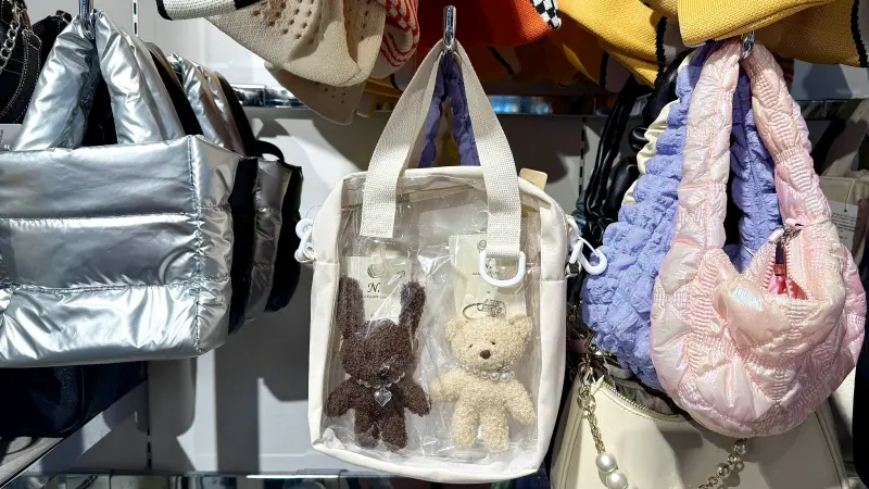 ▲平價實惠的NET一款便宜包包受到眾人盛讚為「神級配件」，新款「透明斜背包」可以裝入喜歡的娃娃，變身超萌「娃包」（也被稱作痛包），大人、小孩都掃貨。（圖／記者蕭涵云攝）