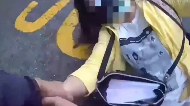 ▲陳姓女子跟人在銀行因抽號碼牌先後順序起口角，北市員警獲報趕往現場，但陳女拒絕盤查，橫躺在馬路上遭警管束，她甚至肘擊員警又吐口水，最後被依妨害公務等罪送辦。（圖／翻攝畫面）