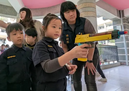 ▲小朋友們拿著手槍、盾牌、警棍和無線電等裝備,擺出超萌英姿拍照,並認識射擊技巧。(圖/高市警局婦幼隊) ▲小朋友們拿著手槍、盾牌、警棍和無線電等裝備,擺出超萌英姿拍照,並認識射擊技巧。(圖/高市警局婦幼隊)