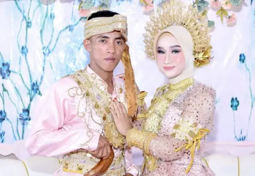 ▲新人穿着粉紅色的傳統武吉士婚禮服裝，並戴上頭飾，女方亦戴上多個金手鐲，可見婚禮十分華麗。（圖／翻攝自《Tribunnews》）  