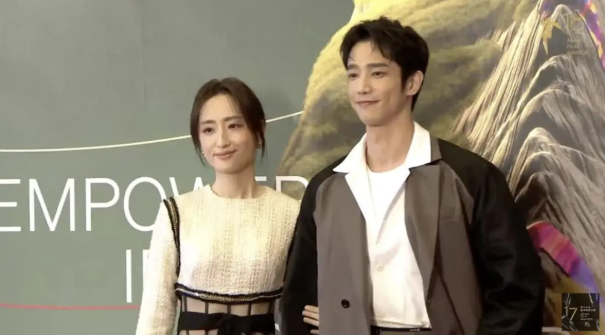 ▲柯佳嬿（左）今（16）日手勾一同合作《童話故事下集》出演夫妻的搭檔劉以豪（右）一同登上亞洲電影大獎，被問到最想見到哪位影星，柯佳嬿坦言役所廣司是她偶像，還自爆手機桌布不是坤達，都是役所廣司的電影海報。（圖／Asian Film Awards Academy YouTube）