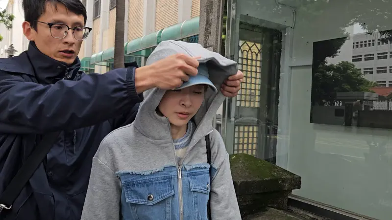 ▲吳安琪(右)身旁護花使者護駕動作2,為她戴起外套帽子。(圖/記者劉松霖攝)