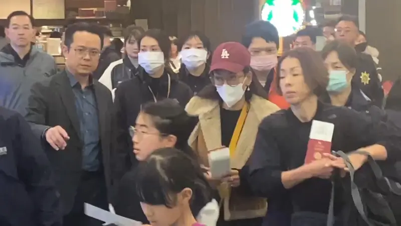 ▲限期離境最後一天,恩綺(紅帽女)抵達松山機場。(圖/記者劉松霖攝影)