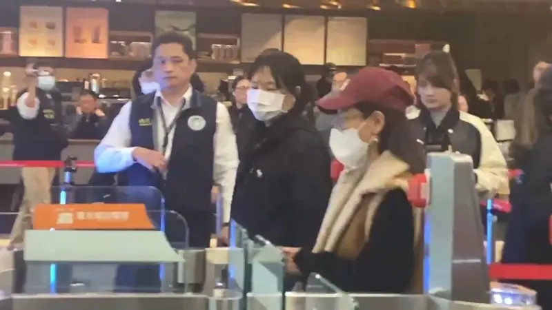 ▲中配恩綺(紅帽女)提前抵達松山機場並出關,八炯來不及堵她嗆聲。(圖/記者劉松霖攝影)
