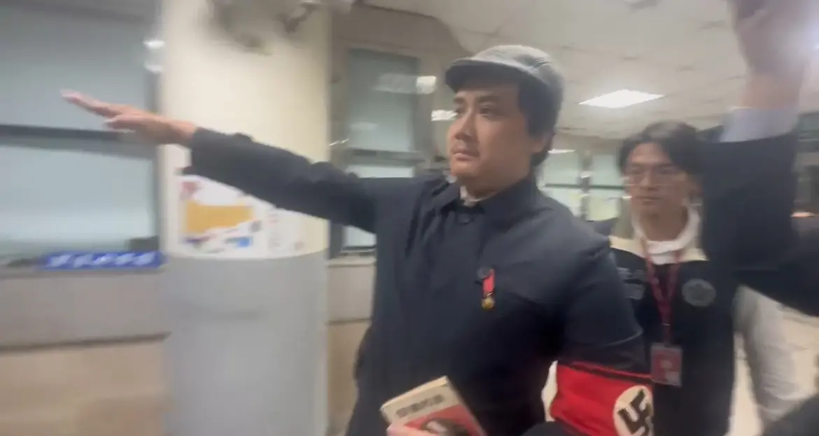 ▲罷免李坤城領銜人宋建樑手臂戴著象徵納粹的「卐」字臂章，手比納粹敬禮手勢，拿著希特勒著作「我的奮鬥」進入偵查大樓引起爭議。（圖／記者嚴俊強攝）
