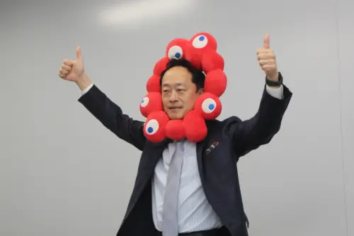 ▲接待台灣媒體團的大阪觀光局統括官田中嘉一頭戴上「脈脈」頭飾，歡迎專程採訪大阪世博。（圖／記者鍾泓良攝影）