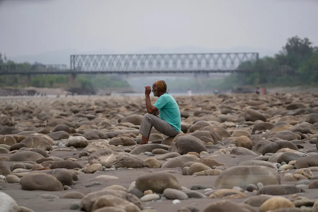 ▲在印度一座水壩切斷水源後，一名男子坐著看幾近乾涸的契那布河。（圖／美聯社／達志影像）
