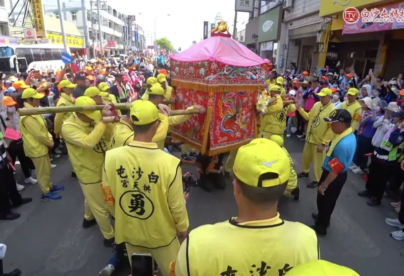 ▲有眼尖網友發現，白沙屯媽祖鑾轎旁總有一位年長男子身穿藍衣、戴紅臂章，神情專注，時不時雙手合十、似乎在向媽祖「請示」，讓人好奇他究竟是誰。（圖／翻攝自白沙屯媽祖網路電視台YT）