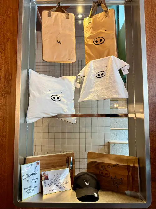 ▲金豬食堂周邊商品（尚未在台販售）；造訪韓星簽名板。（圖／記者蕭涵云攝）