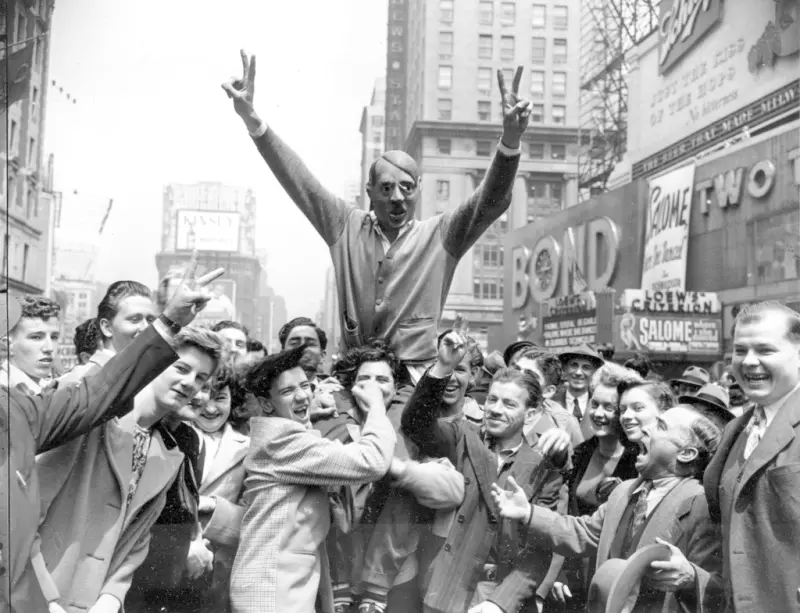 <p>▲1945年5月7日，人們在紐約時代廣場慶祝二戰結束，一群人聚集在戴著希特勒面具的少年周圍，慶祝德國投降。（圖／達志影像／美聯社）</p>