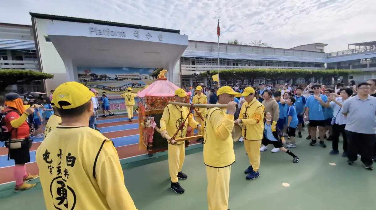 ▲白沙屯媽祖今（8）日回鑾途中鑾轎特別轉進彰化埔鹽國小賜福，活動現場卻爆發插隊爭議，一名戴帽女教職員當眾從小學生手中奪走結緣品，畫面被拍下並在網路瘋傳。（圖／翻攝自白沙屯媽祖網路電視台YT）