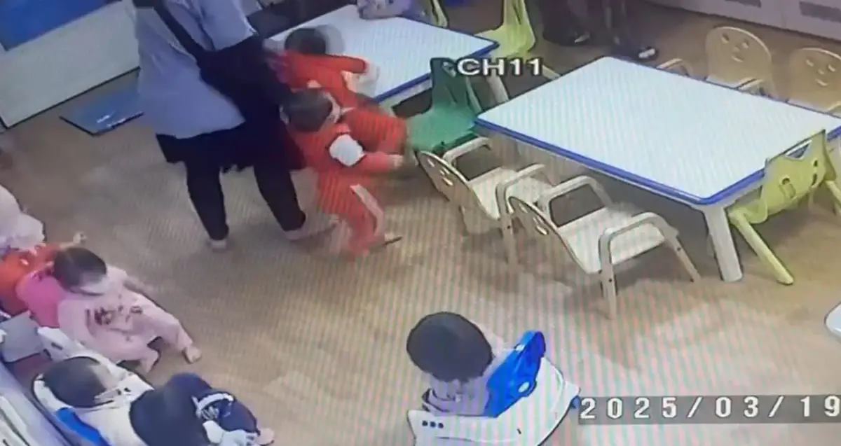 ▲女保育員右手拉著一名幼兒，左手扯著另名幼兒的後衣領，將她從椅子上拎起。（圖／台中市議員陳清龍提供，2025.05.12）