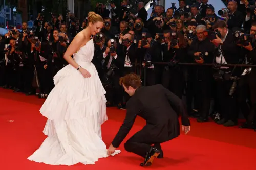 ▲羅伯派汀森（右）蹲下為珍妮佛勞倫斯調整裙襬，免得自己又踩到。（圖／美聯社／達志影像）