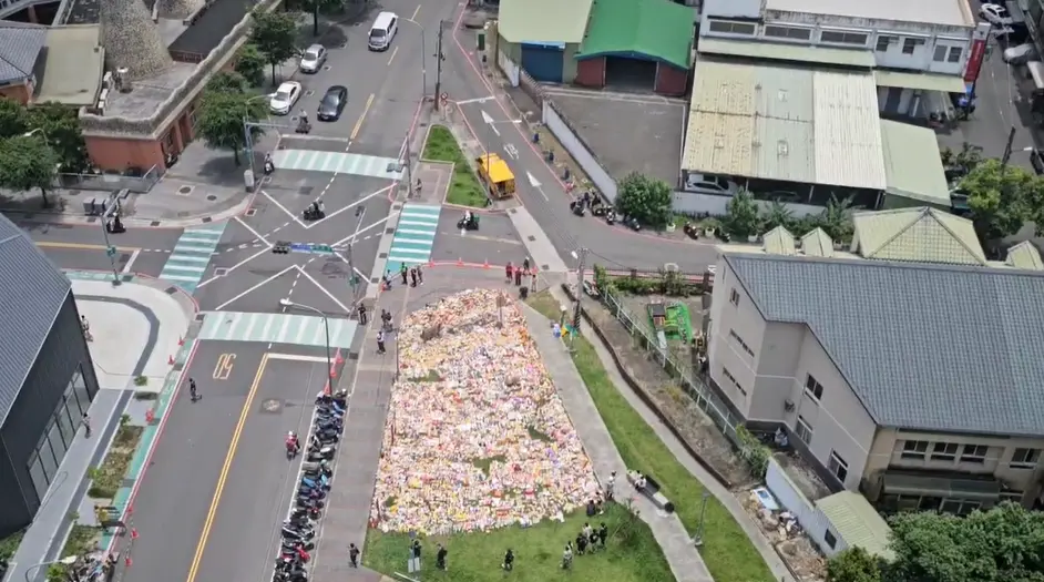 ▲三峽車禍哀悼死者的花束及物資，今日上午已堆積約400平方公尺，公園一半空間都被占據，數量驚人。（圖／翻攝畫面）