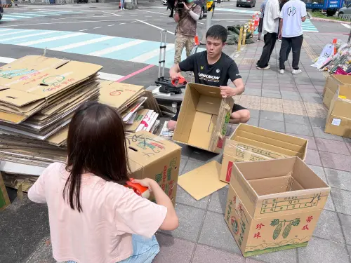 ▲三峽車禍現場附近居民，自願提供100個紙箱，協助現場志工將悼念死者的祭品和鮮花分類。（圖／記者徐敏娟攝）