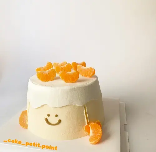 ▲店家將近期爆紅的難哄蛋糕做成橘子口味，上方與側邊以新鮮砂糖橘瓣點綴，整體色調清新，搭配可愛的笑臉裝飾，充滿溫暖與幸福感。（圖／業者提供）