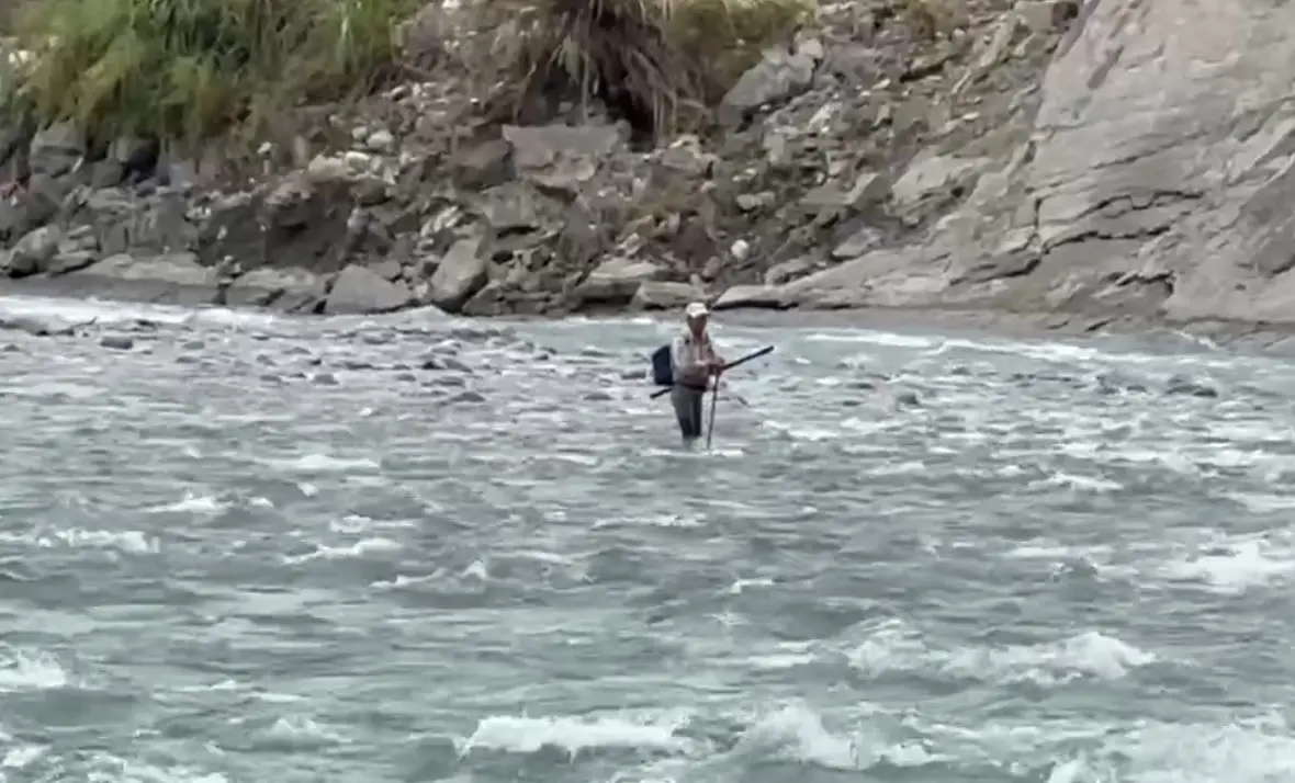 ▲受困沙洲的老翁站在湍急溪水中，手上還緊緊拿著釣竿。（圖／台中市消防局提供，2025.06.12）